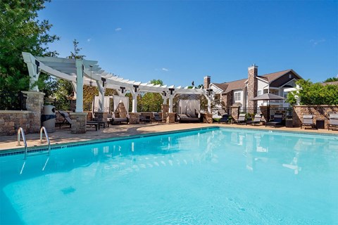 a swimming pool with a pergola over it and a house in the background