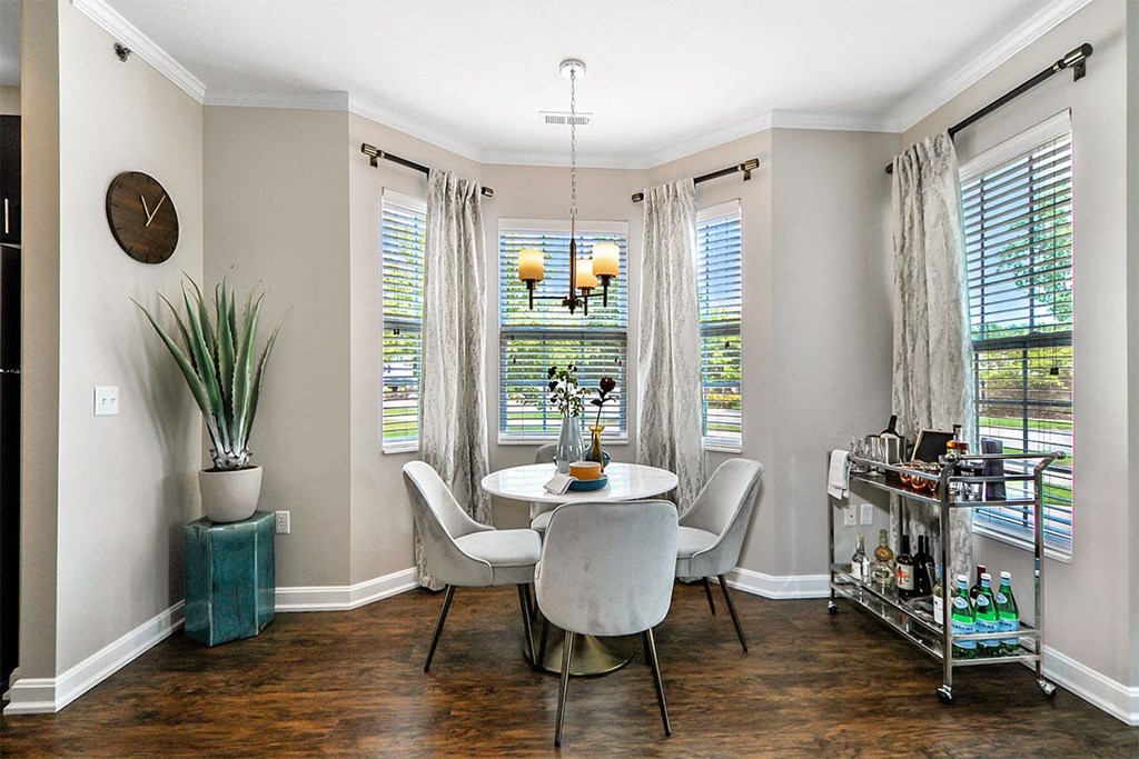 a dining room with three windows and a table and chairs