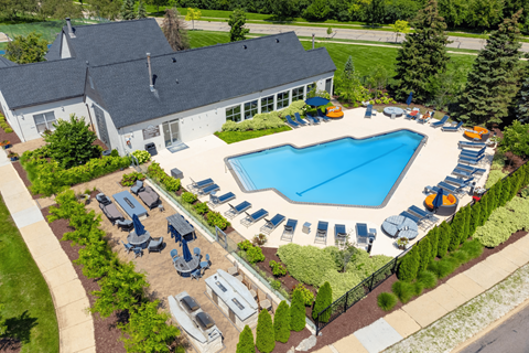 A large swimming pool surrounded by sun loungers and trees.