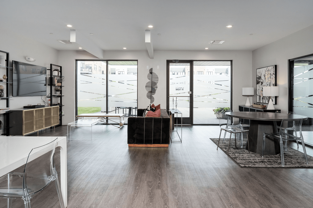 A modern living room with a black sofa and a glass table.