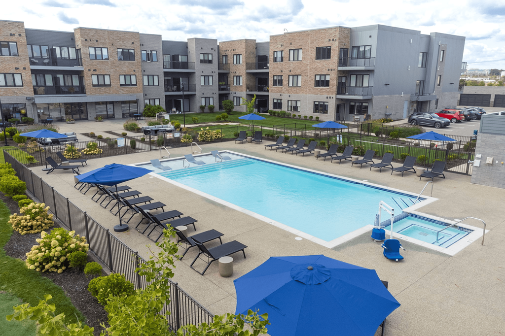 A large swimming pool surrounded by blue umbrellas and lounge chairs.