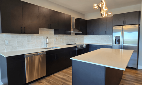 A modern kitchen with dark brown cabinets and a white countertop.