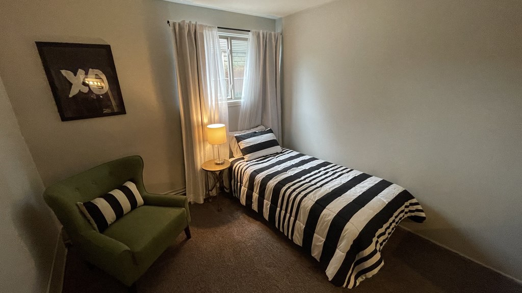 a small bedroom with a bed and a green chair