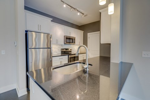 A modern kitchen with a stainless steel refrigerator and a granite countertop.