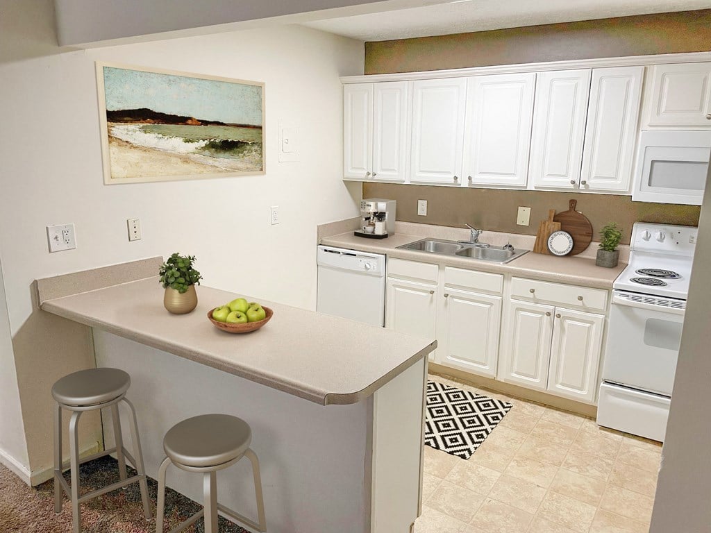 a kitchen with white cabinets and a counter with two stools