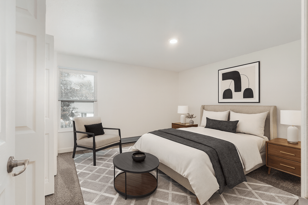 A bedroom with a large bed, a chair, and a table.