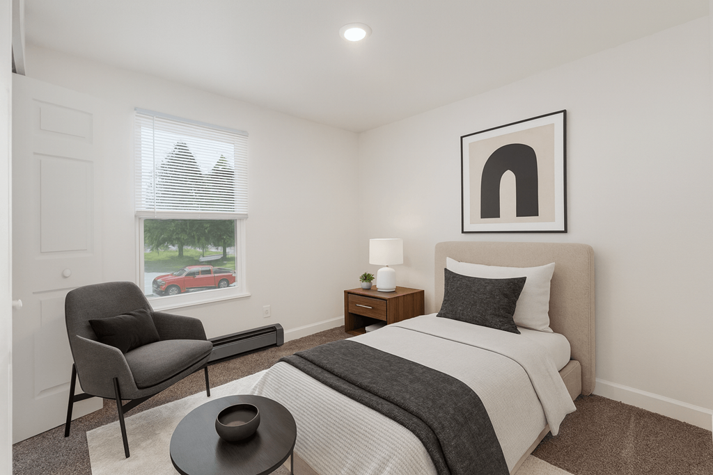 A bedroom with a bed, chair, and window.