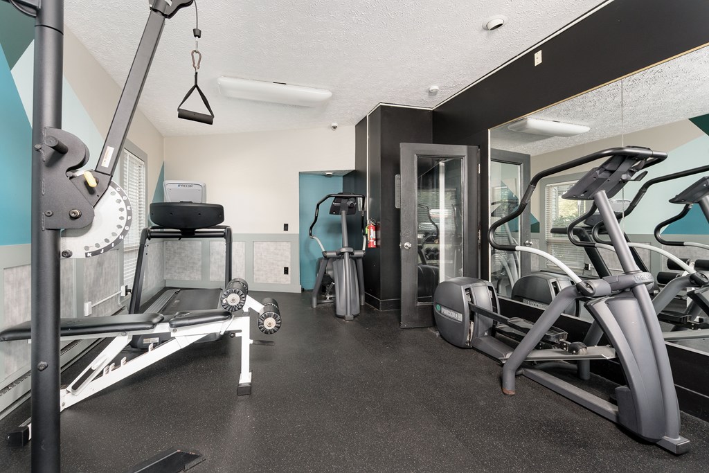 A gym with a variety of equipment including treadmills, weights, and exercise machines.