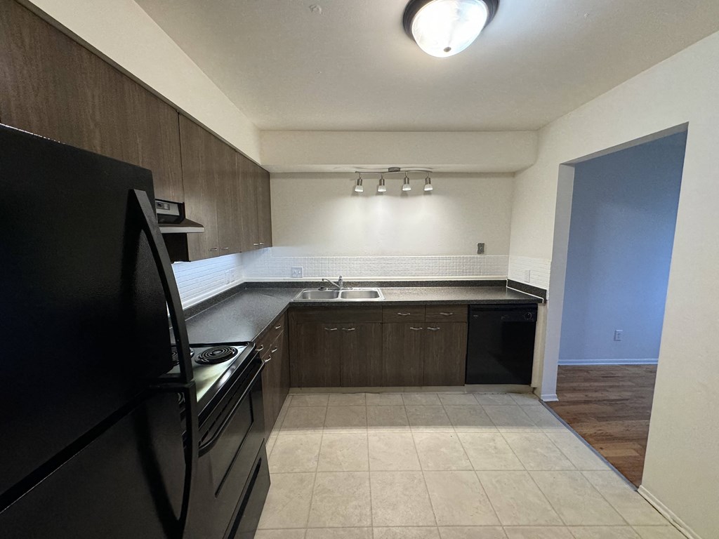An empty kitchen with black appliances and wooden cabinets