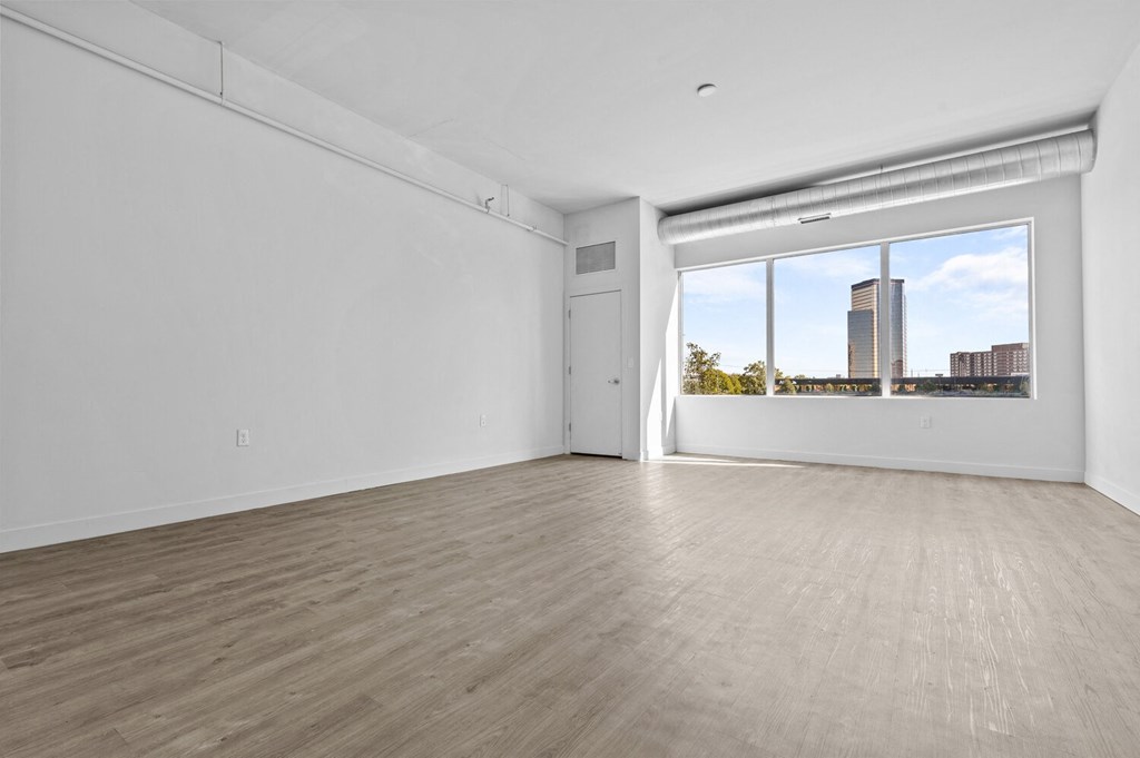 a bedroom with hardwood floors and a large window
