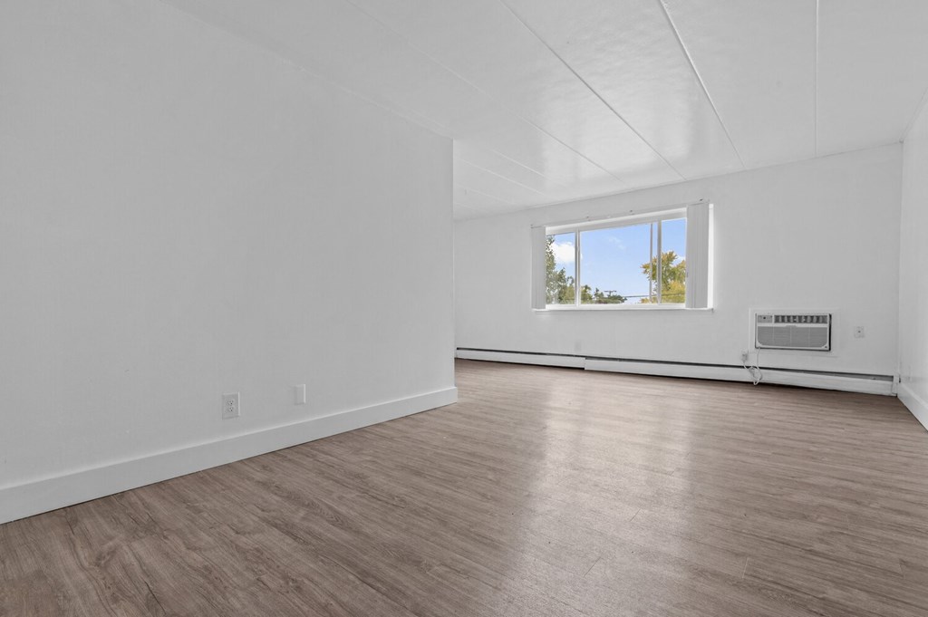an empty living room with white walls and a window