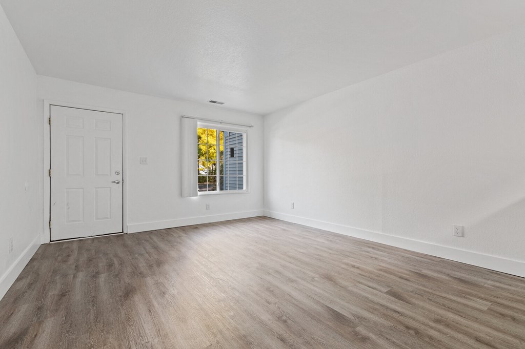 an empty living room with white walls and wood flooring