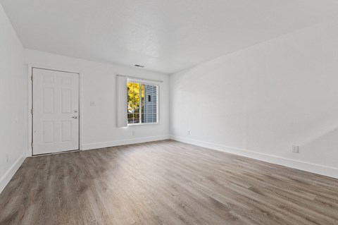 an empty living room with white walls and wood flooring