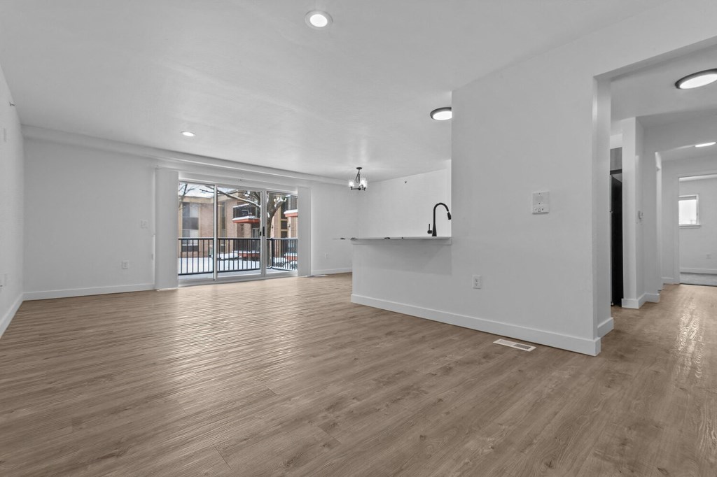 the living room and kitchen of a new home with white walls and wood floors