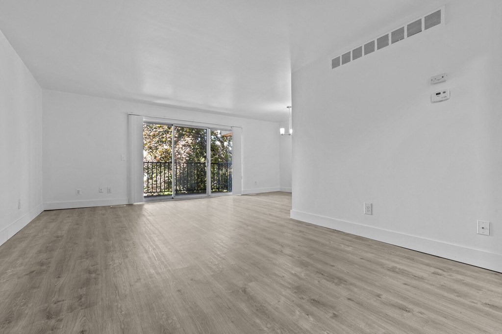 the living room and dining room of a new home with white walls and wood floors