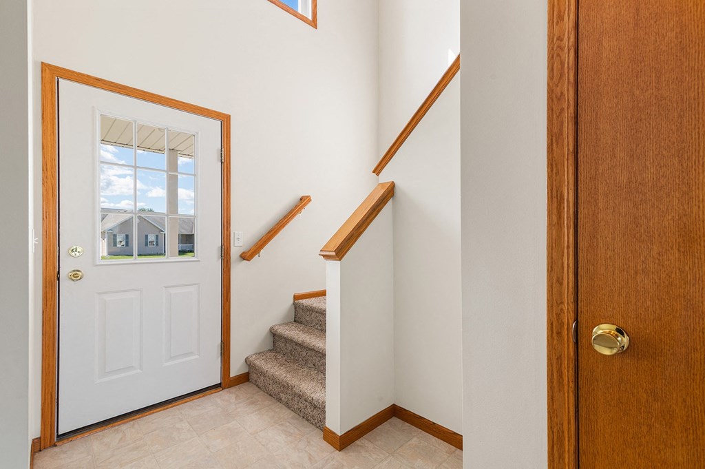 a entryway with a white door and a staircase with stairs