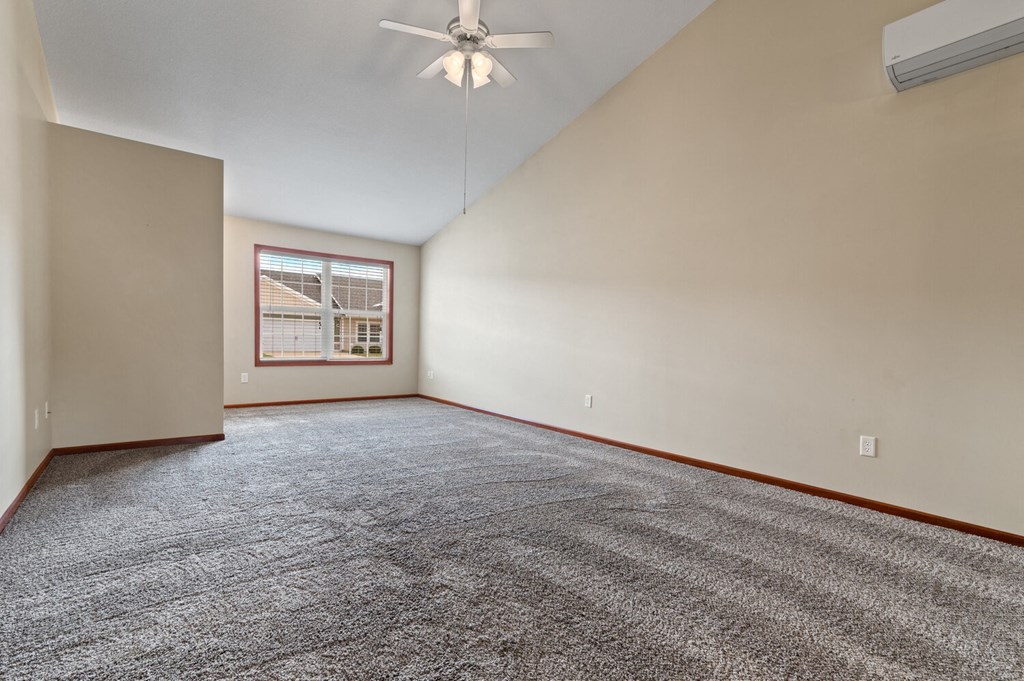 an empty living room with a ceiling fan and a window