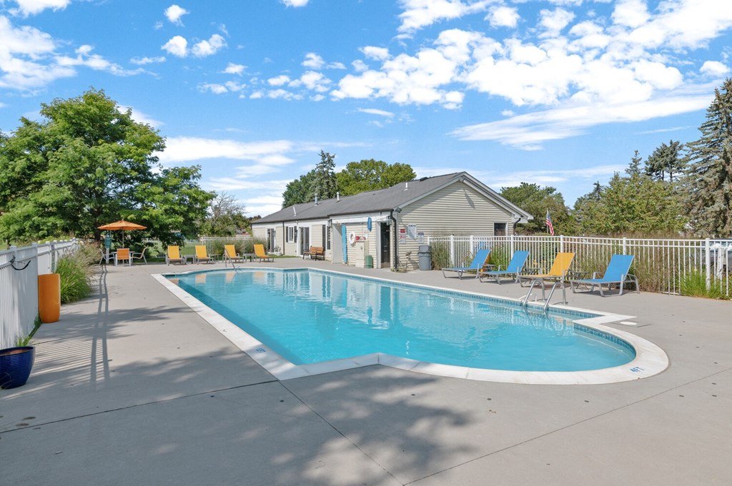 a swimming pool with lounge chairs and a building in the background