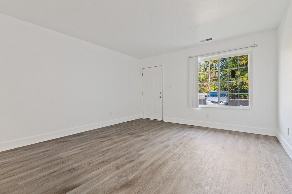 an empty living room with white walls and a window
