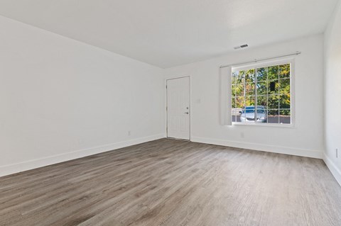 an empty living room with white walls and a window