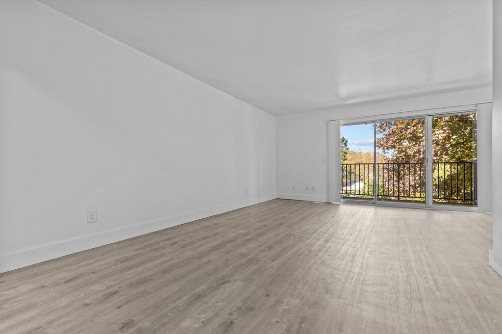 an empty living room with a sliding glass door to a balcony