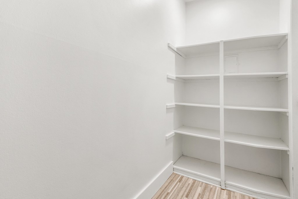 an empty room with white shelves and a wooden floor