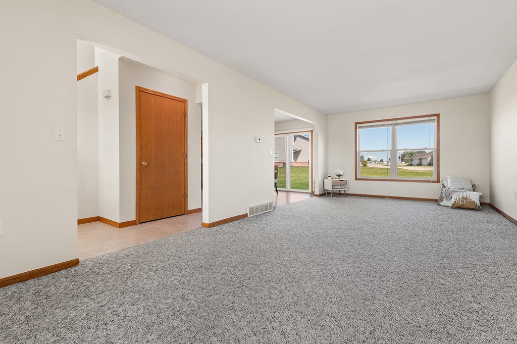 the living room of a house with a carpeted floor and a wooden door