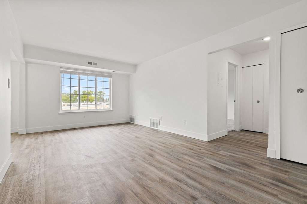 an empty living room with white walls and a window