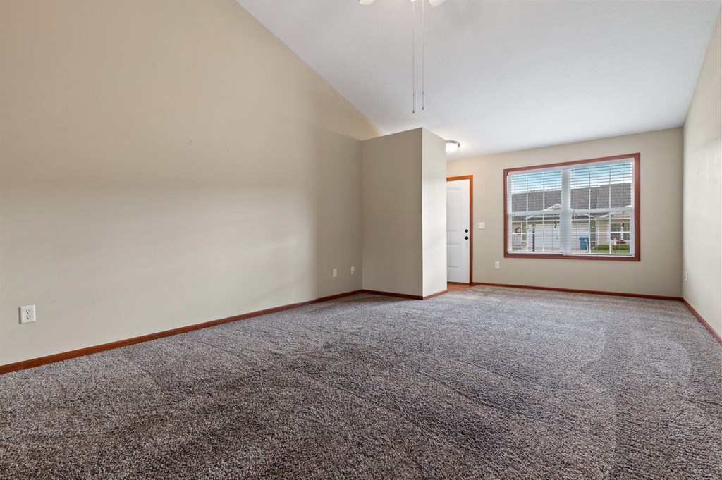 an empty living room with carpet and a window