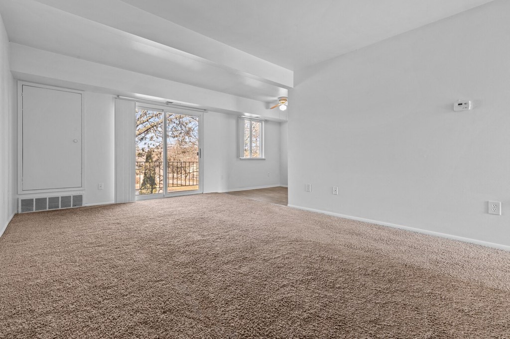 an empty living room with a door to a balcony