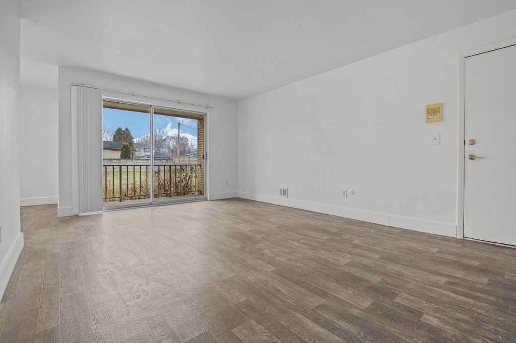 an empty living room with a sliding glass door to a balcony