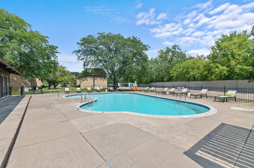 a swimming pool with chaise lounge chairs and trees in the background