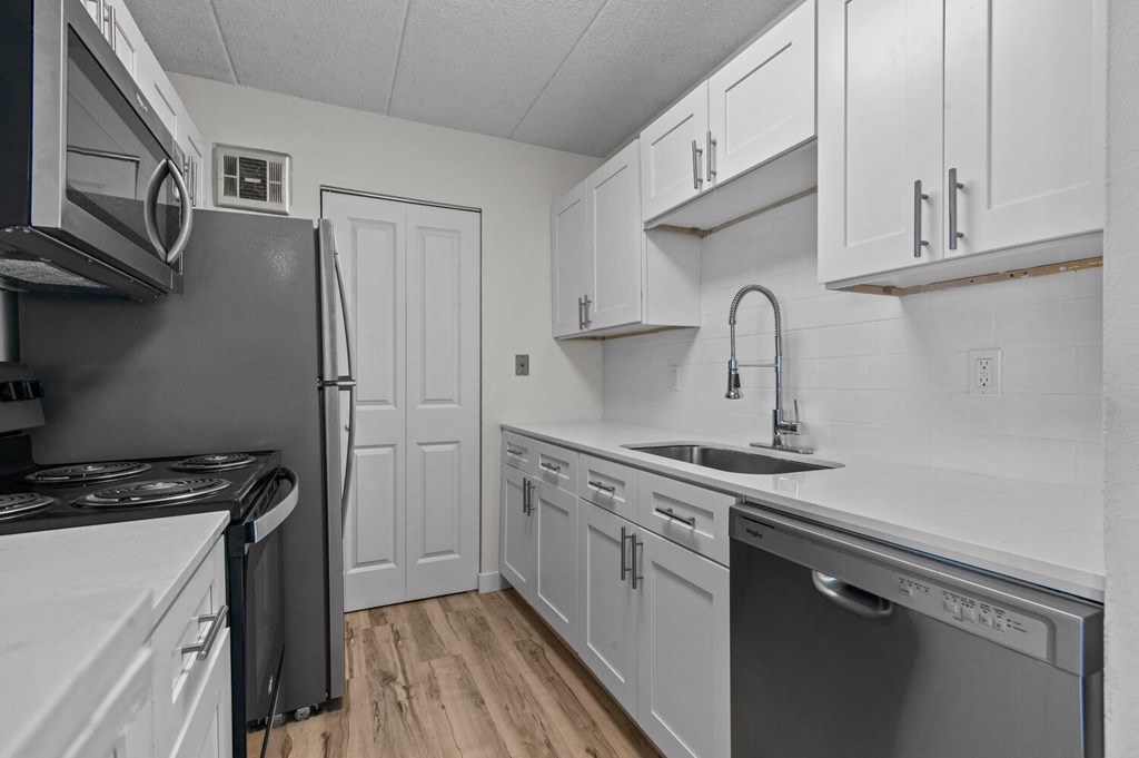 an empty kitchen with white cabinets and stainless steel appliances