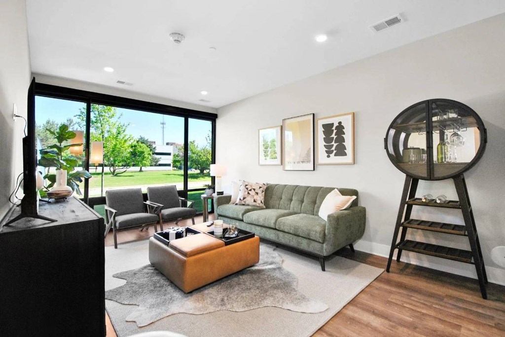 A living room with a green couch, a brown coffee table, and a large window.