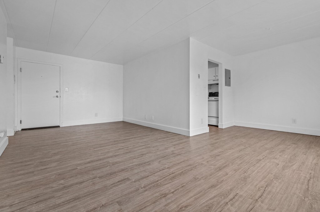 the living room of an empty apartment with white walls and wood floors