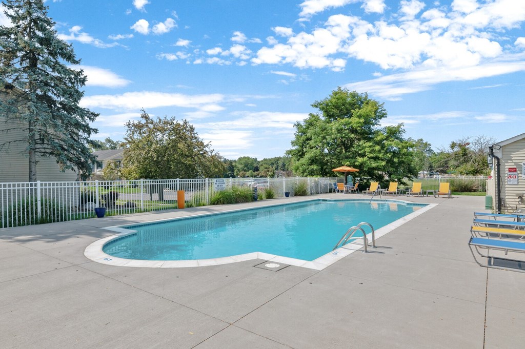 a swimming pool with a fence and trees in the background