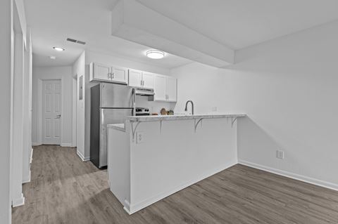 the kitchen and living room in a renovated apartment with white walls and wood flooring