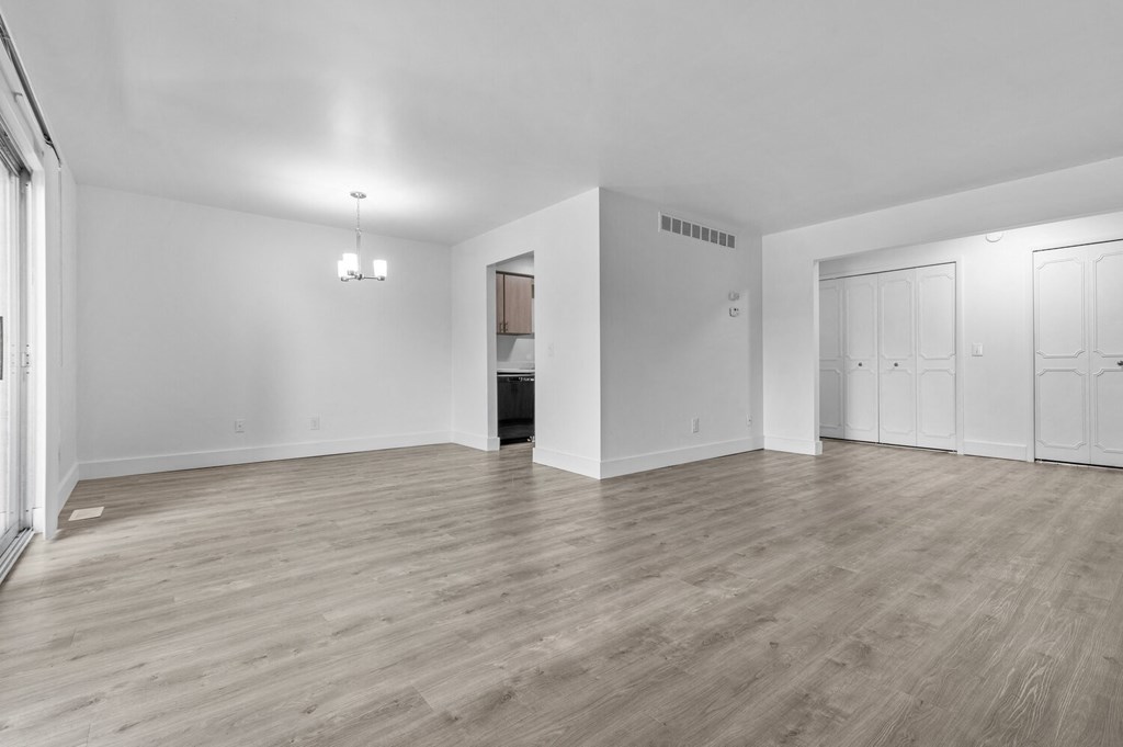 an empty living room with white walls and wood flooring