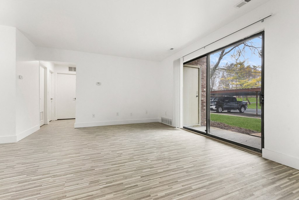 an empty living room with a large window and wood flooring