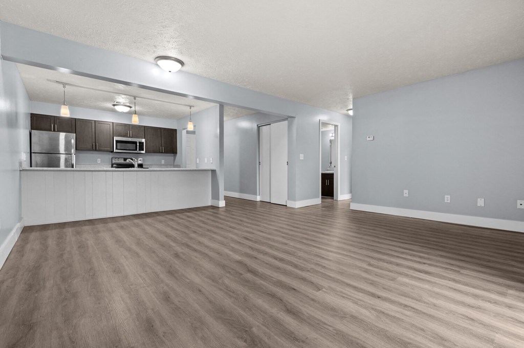 the living room and kitchen of an empty apartment with wood flooring