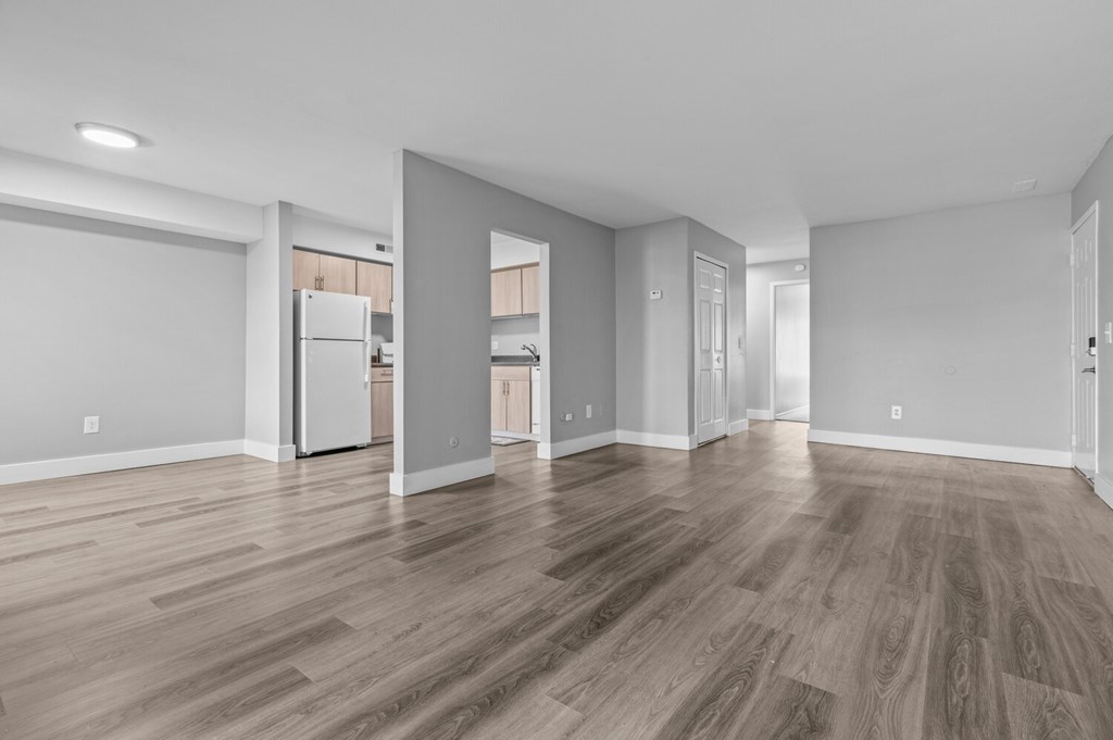 A spacious room with wood flooring and white walls.