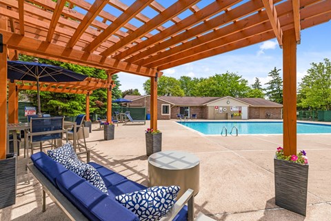 A wooden pergola over a pool area with a blue lounger.