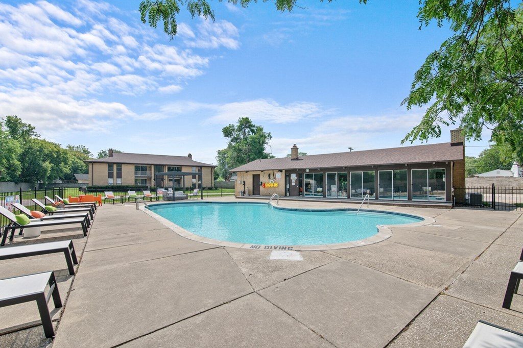 a swimming pool with chaise lounge chairs and a building in the background