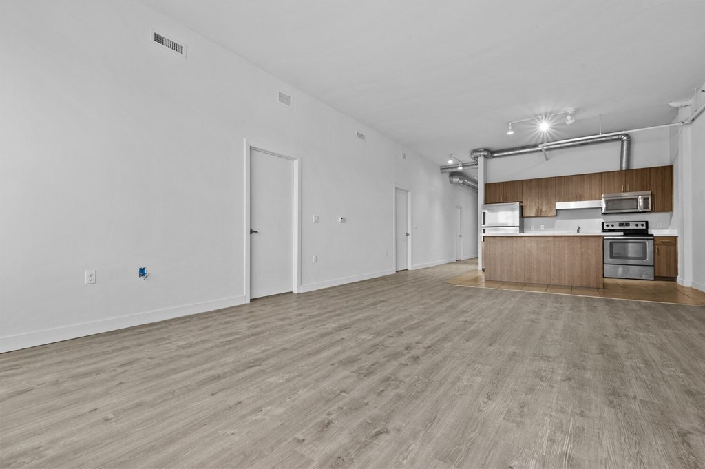 a spacious living room with white walls and hardwood floors