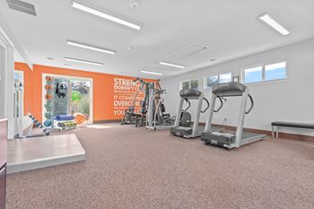 a gym with a lot of exercise equipment on the floor and a wall with a motivational quote