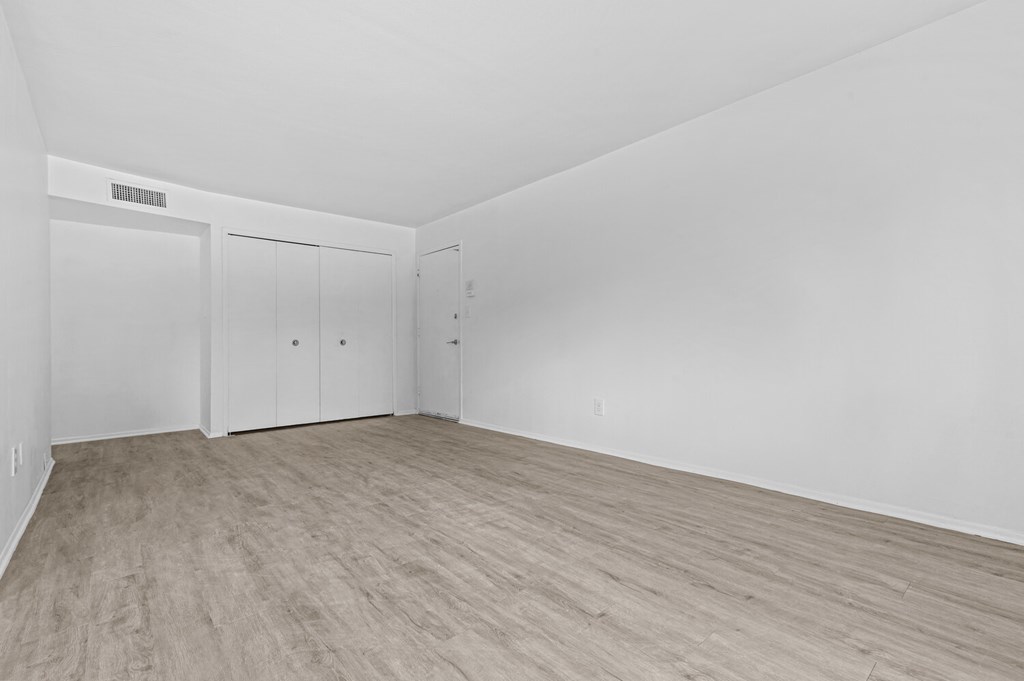 a bedroom with hardwood floors and white walls