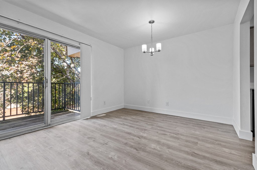 an empty living room with a sliding glass door to a balcony