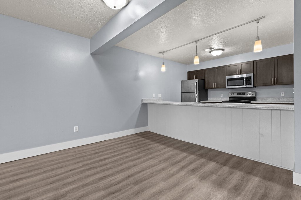 the living room and kitchen of an apartment with wood flooring and a counter top