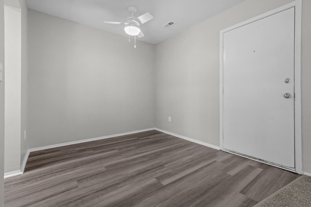 an empty room with wood flooring and a ceiling fan
