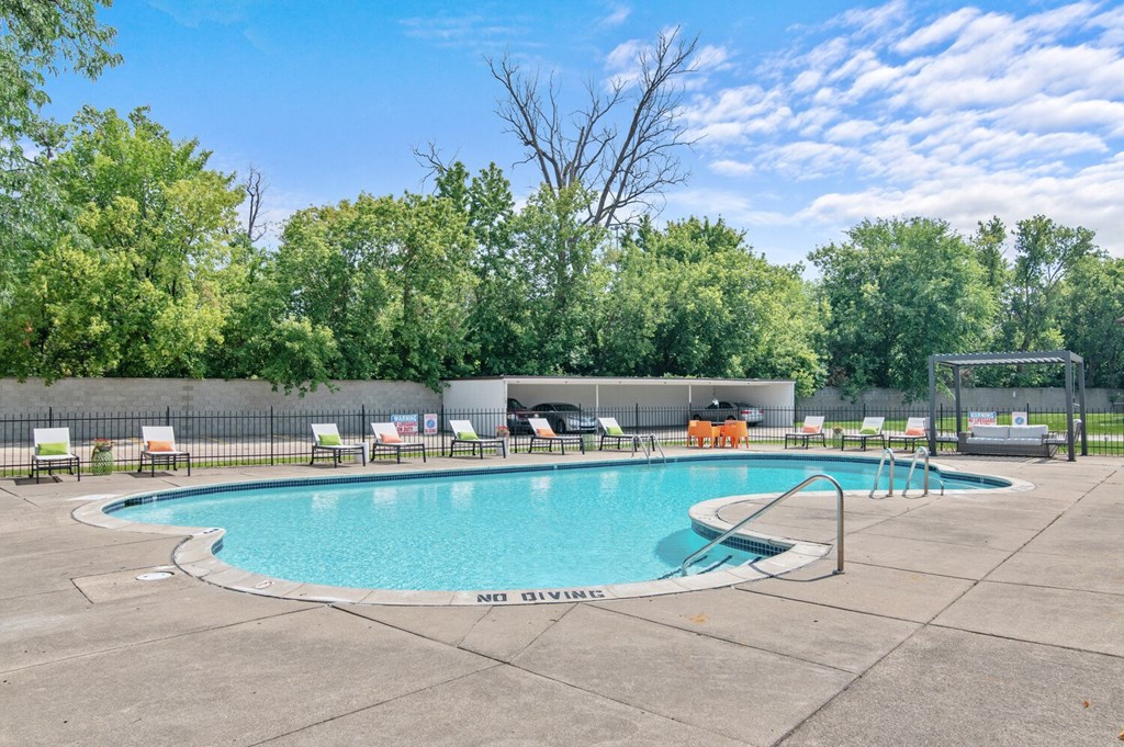 a swimming pool with chaise lounge chairs and trees in the background